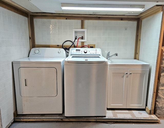 laundry room featuring washer and dryer, sink, tile walls, and cabinets