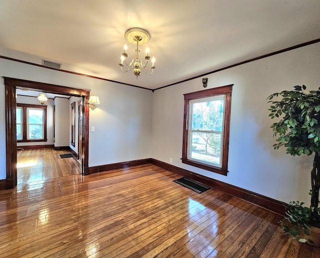 unfurnished room with ornamental molding, wood-type flooring, and a notable chandelier