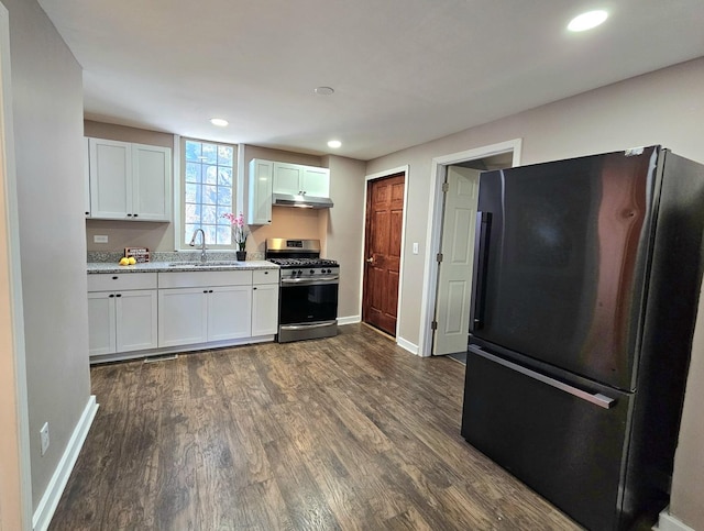 kitchen featuring dark wood-type flooring, sink, stainless steel gas stove, black fridge, and white cabinets