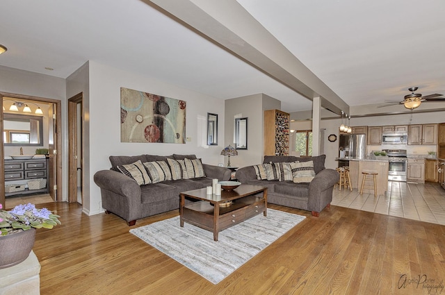 living room with ceiling fan with notable chandelier and light hardwood / wood-style flooring