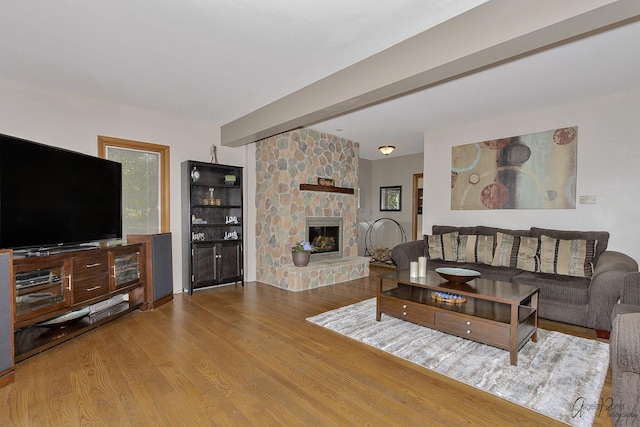 living room featuring wood-type flooring and a stone fireplace