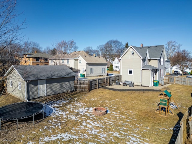 yard layered in snow featuring an outdoor fire pit, an outdoor structure, and a trampoline