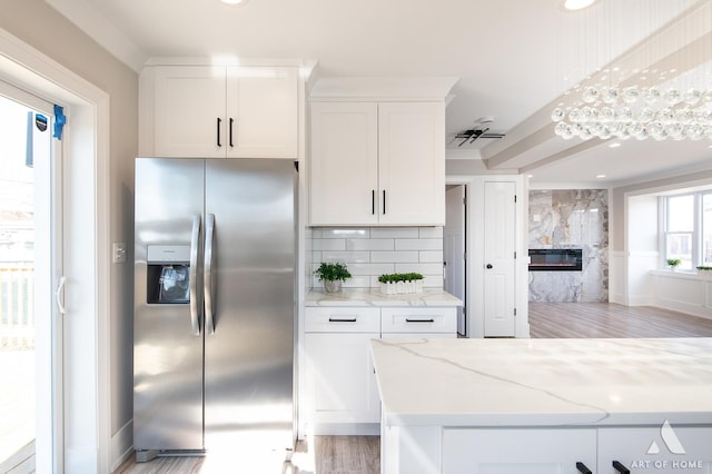 kitchen with white cabinetry, decorative backsplash, light stone counters, and stainless steel fridge with ice dispenser