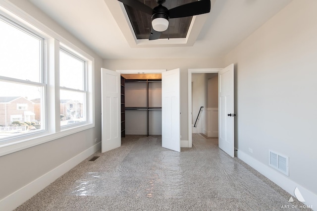 unfurnished bedroom featuring ceiling fan, a raised ceiling, and a closet