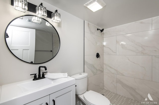 bathroom featuring vanity, toilet, and a tile shower