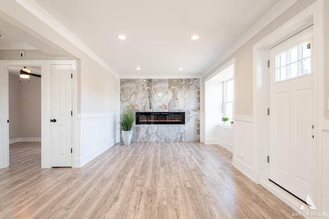 unfurnished living room featuring crown molding, a fireplace, and light wood-type flooring