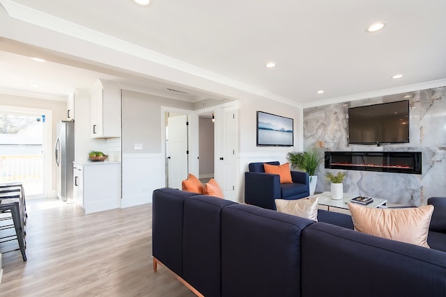 living room with ornamental molding, a fireplace, and light hardwood / wood-style floors