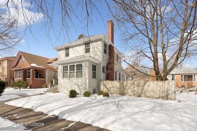 exterior space with a fenced front yard, a chimney, and stucco siding