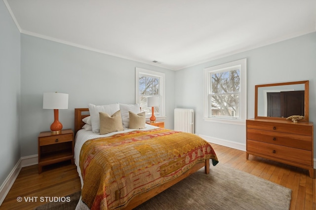 bedroom featuring radiator heating unit, baseboards, wood-type flooring, and ornamental molding