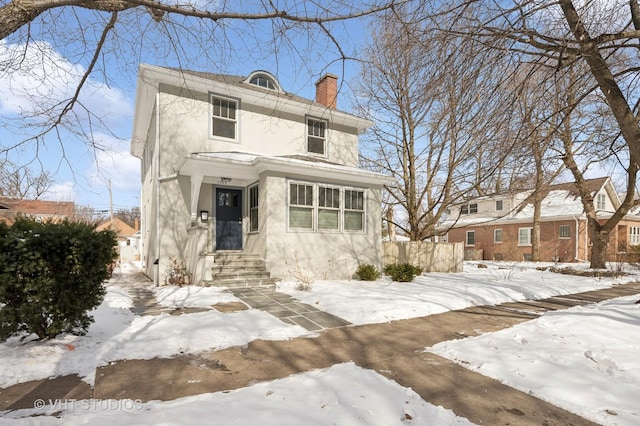 traditional style home with a chimney, fence, and stucco siding