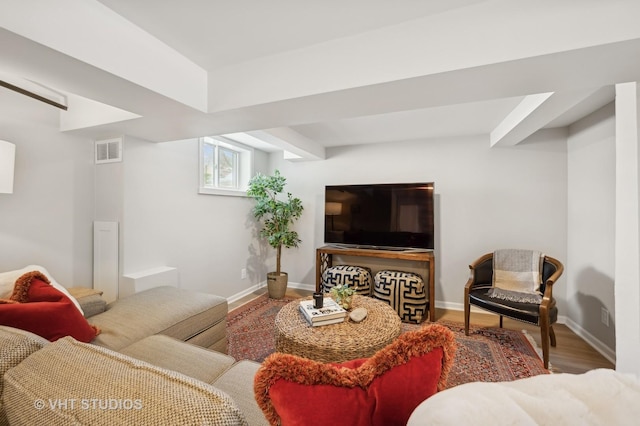 living room featuring wood finished floors, visible vents, and baseboards