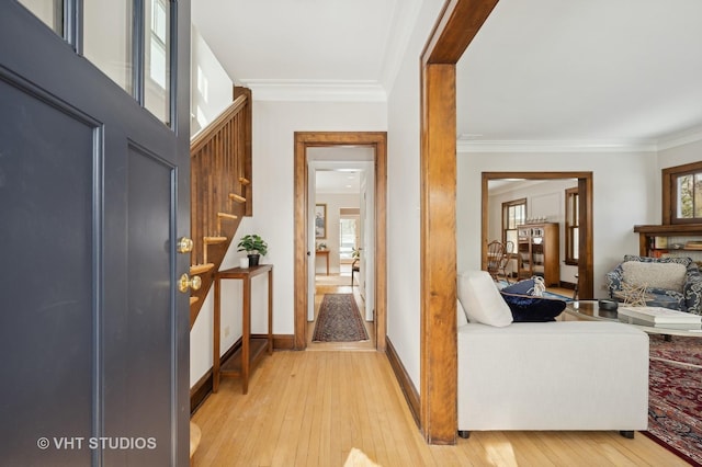 foyer entrance featuring plenty of natural light, crown molding, and light wood finished floors