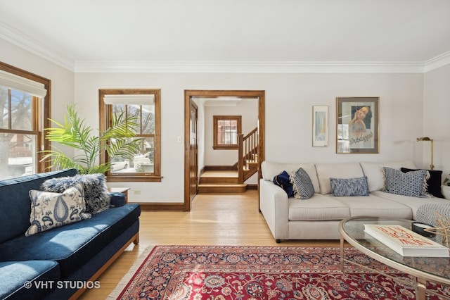 living room featuring ornamental molding, light wood-style floors, stairway, and a healthy amount of sunlight