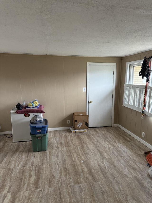 interior space with wooden walls and a textured ceiling