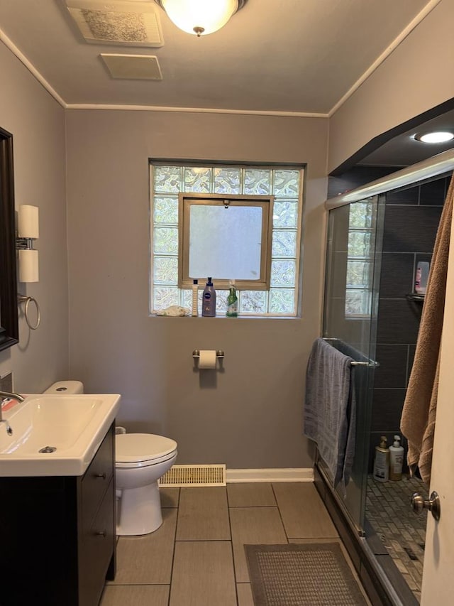 bathroom with tile patterned flooring, vanity, a shower with shower door, and toilet