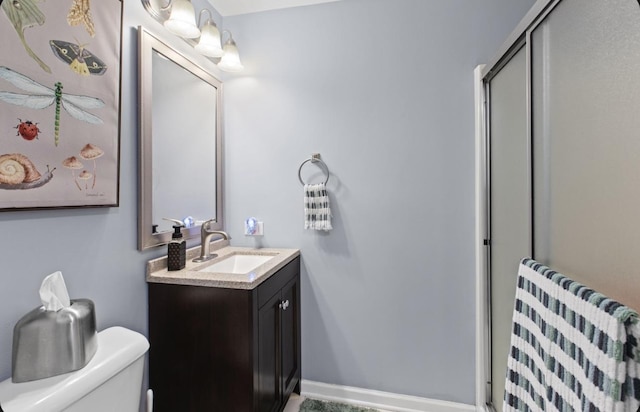 bathroom with baseboards, toilet, a shower stall, and vanity