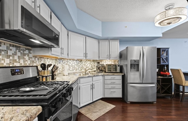 kitchen featuring stainless steel appliances, dark wood-style flooring, a sink, and decorative backsplash