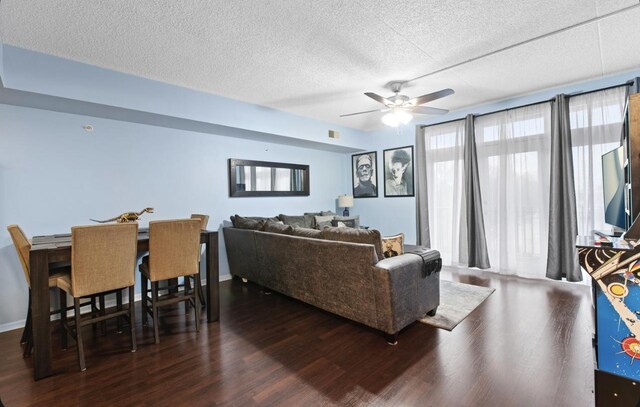 living room featuring ceiling fan, dark wood-type flooring, and a textured ceiling