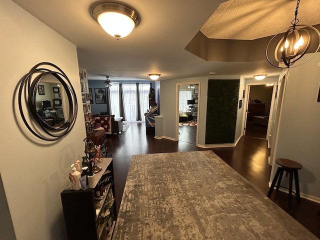 hallway with dark hardwood / wood-style floors and a chandelier