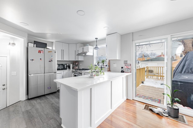 kitchen with pendant lighting, white cabinets, light hardwood / wood-style floors, kitchen peninsula, and stainless steel appliances