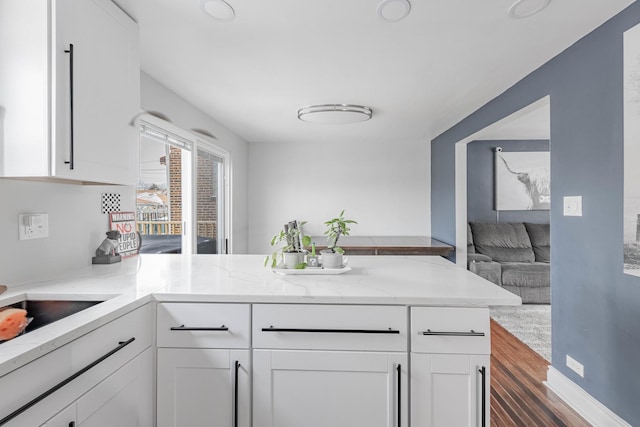 kitchen featuring white cabinetry, light stone countertops, and kitchen peninsula