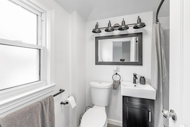 bathroom featuring vanity, lofted ceiling, walk in shower, and toilet