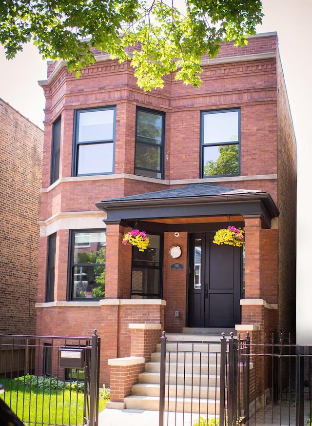 view of front facade with covered porch, a fenced front yard, a gate, and brick siding