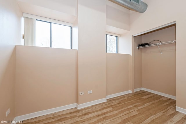 unfurnished bedroom featuring light wood finished floors, a closet, and baseboards