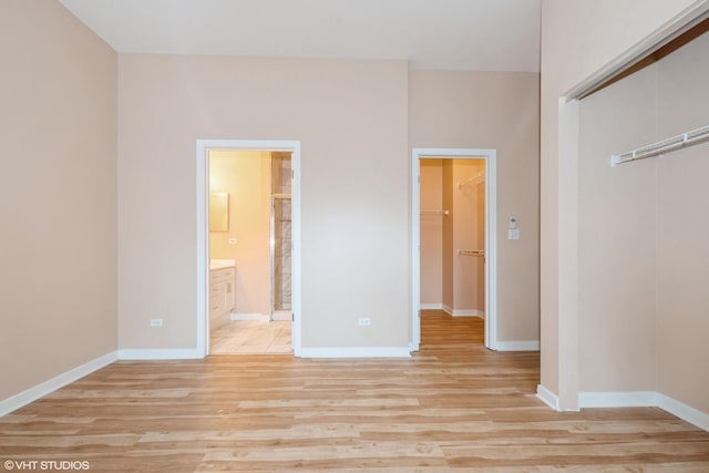 unfurnished bedroom with light wood-style floors, baseboards, a closet, and ensuite bathroom