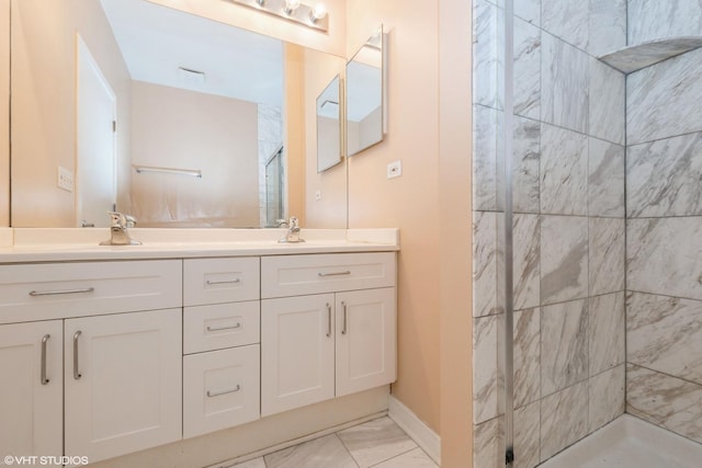 full bath with double vanity, a stall shower, baseboards, marble finish floor, and a sink