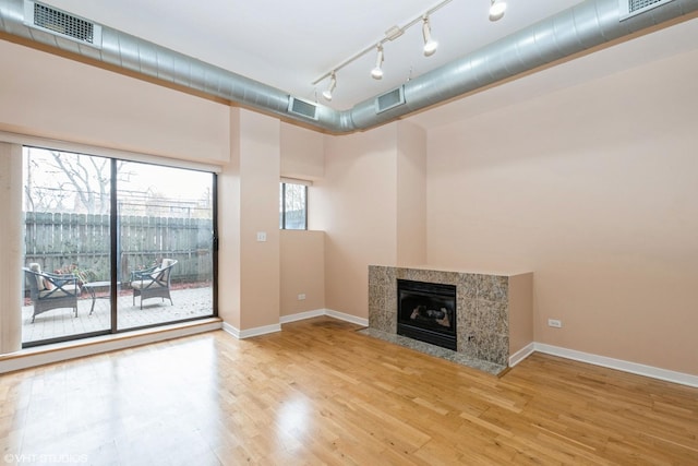 unfurnished living room with baseboards, a fireplace, visible vents, and wood finished floors