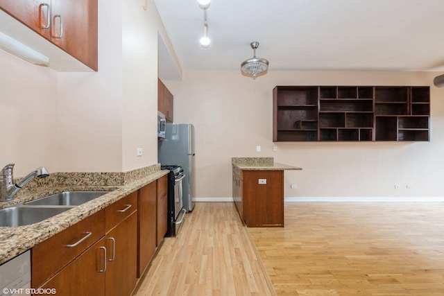 kitchen featuring dishwasher, light stone counters, gas range oven, open shelves, and a sink