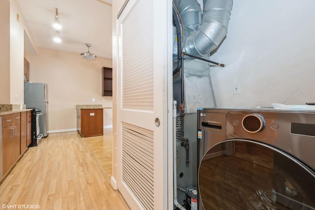 interior space with brown cabinetry, stacked washer and dryer, light wood-style floors, and baseboards