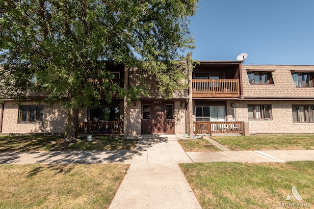 view of front of house with a front yard and a balcony