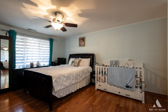 bedroom with dark hardwood / wood-style flooring, crown molding, and ceiling fan