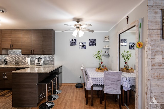 dining area featuring crown molding, ceiling fan, sink, and light wood-type flooring