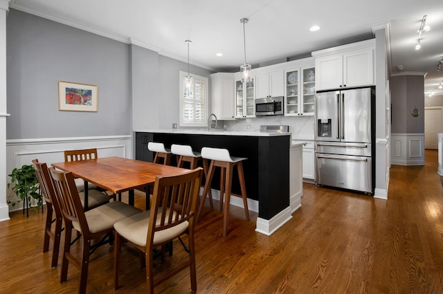 dining space with ornamental molding, sink, and dark hardwood / wood-style flooring