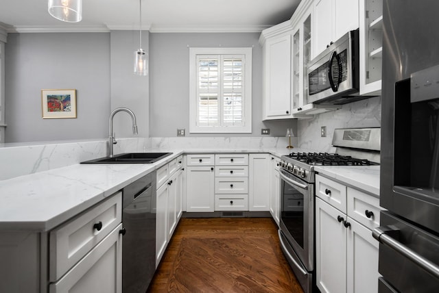 kitchen featuring appliances with stainless steel finishes, decorative light fixtures, white cabinetry, sink, and light stone counters