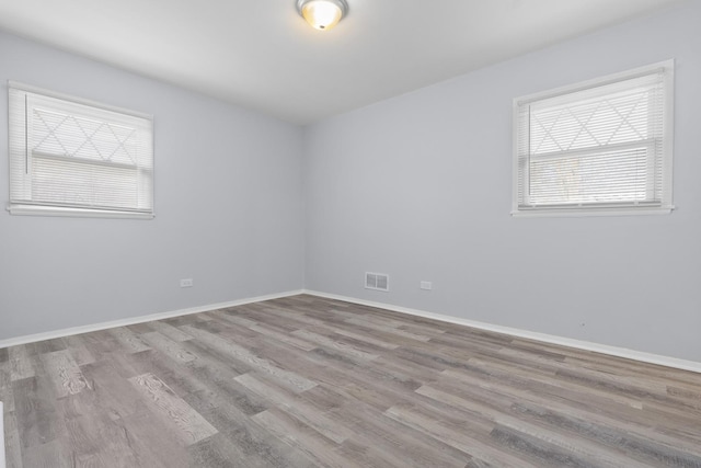 spare room with light wood-style flooring, visible vents, and baseboards