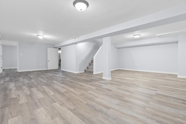 finished basement with baseboards, light wood finished floors, and stairs