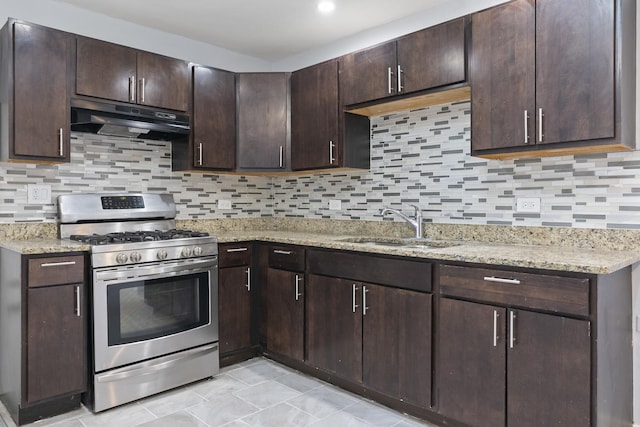 kitchen featuring dark brown cabinetry, stainless steel gas range oven, light stone counters, under cabinet range hood, and a sink