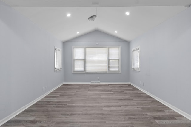 empty room with visible vents, baseboards, lofted ceiling, light wood-style flooring, and recessed lighting