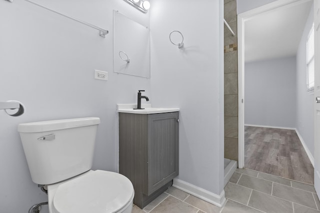 bathroom featuring toilet, a shower stall, vanity, baseboards, and tile patterned floors