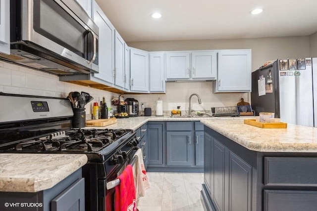 kitchen featuring blue cabinets, sink, a center island, appliances with stainless steel finishes, and decorative backsplash