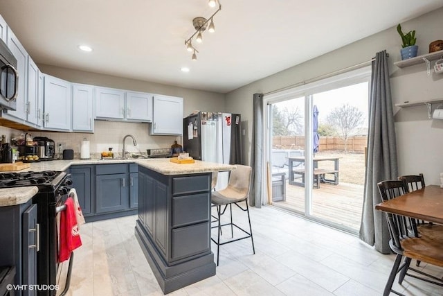 kitchen featuring sink, a breakfast bar area, a center island, tasteful backsplash, and gas range