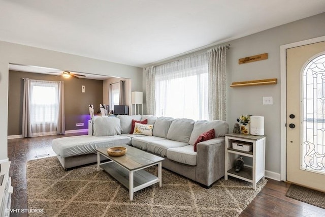 living room featuring dark wood-type flooring and ceiling fan