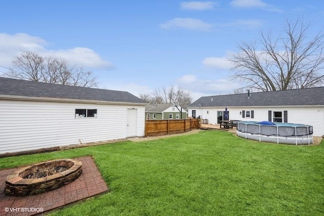 view of yard with a pool side deck and a fire pit