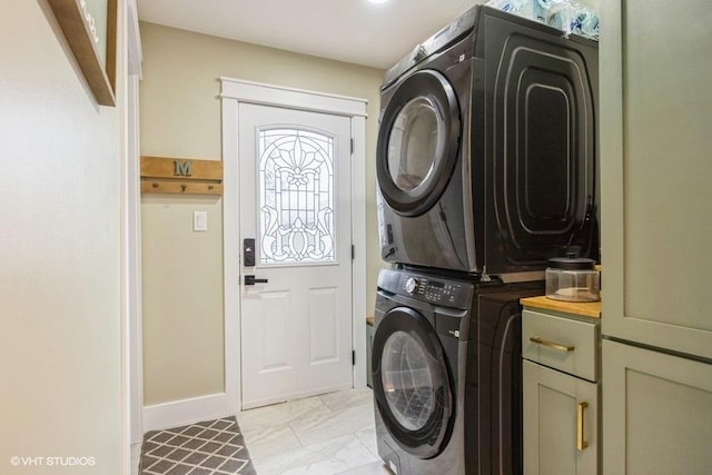 clothes washing area featuring stacked washer and dryer and cabinets