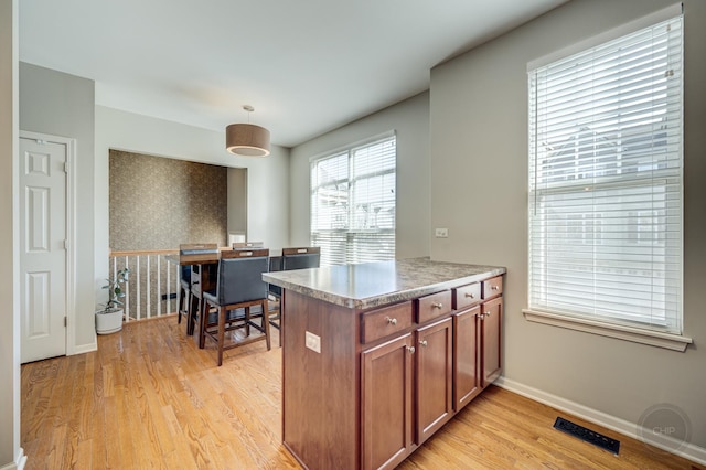 3460 Bradbury Cir, Aurora, IL 60504 - kitchen with brown cabinets, light wood-style flooring, baseboards, wallpapered walls, and hanging light fixtures