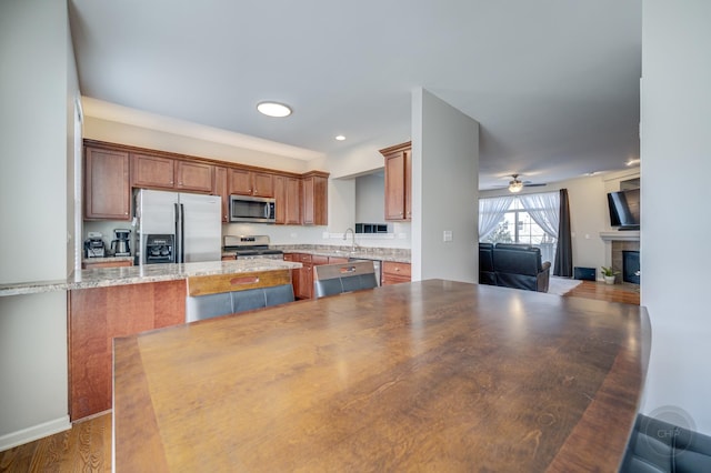3460 Bradbury Cir, Aurora, IL 60504 - kitchen with stainless steel appliances, a peninsula, open floor plan, a tiled fireplace, and recessed lighting
